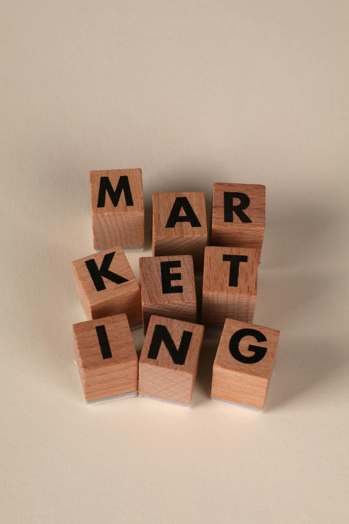 Wooden blocks arranged to spell 'MARKETING' on a neutral background.